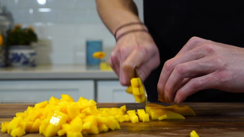 a man cuts a mango with a knife on the table